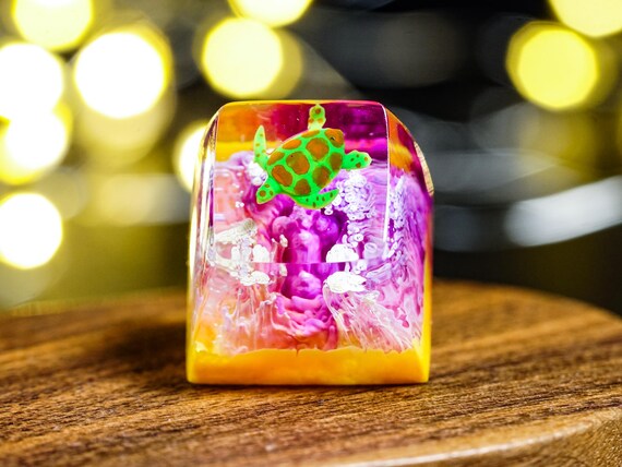 A hand-poured resin artisan keycap with a tiny ocean scene and sea turtle inside — the kind of obsessive miniature craft that mechanical keyboard nerds lose their minds over.