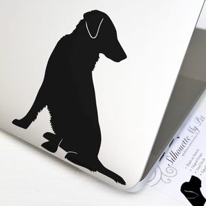 May include: Black silhouette of a dog sitting on a white laptop. The dog is facing to the left and has its tail curled around its legs. The laptop is open and has a white background. The image is a sticker that can be applied to a laptop.