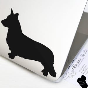 May include: A black vinyl decal in the shape of a Corgi dog silhouette applied to the lid of a silver laptop. Next to the laptop is a white business card with the text Silhouette My Pet, Hand-cut Artwork, Original Designs, Vinyl Decals, Upcycled Book Pages.