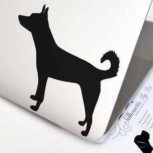 May include: Black silhouette of a dog standing on a white surface. The dog has a curved tail and pointed ears. A business card with the text "Silhouette My Pet" and a dog silhouette is visible.