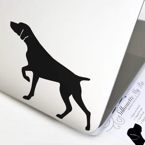 May include: Black silhouette of a German Shorthaired Pointer dog on a white laptop. The dog is standing with its head turned to the left. The laptop is closed and the screen is facing the viewer. The image is a sticker for a laptop.