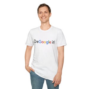 Könnte beinhalten: Weißes T-Shirt mit dem Text "DeGoogle it!" in einer bunten, mehrfarbigen Schrift. Das Shirt hat kurze Ärmel und wird von einer Person in Jeans getragen.
