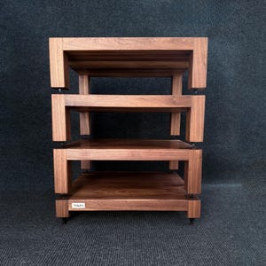 May include: A three-tiered wooden audio rack with a rich, dark brown finish. The rack features a sturdy, open design with rectangular shelves supported by thick, square legs. The brand name "TAFI" is visible on the bottom shelf.