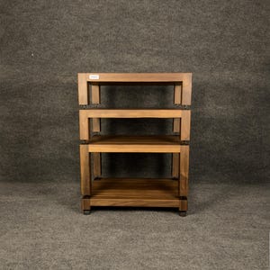 Könnte beinhalten: Ein dreistufiges Holzregal mit warmbraunem Finish. Die Regale sind rechteckig und werden von stabilen, quadratischen Beinen getragen. Das Regal ist für die Aufbewahrung oder Präsentation konzipiert, mit einer schlichten, modernen Ästhetik.