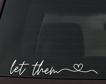 May include: White vinyl decal with the words "let them" in a cursive font, followed by a heart symbol. The decal is designed to be applied to a car window or similar surface.