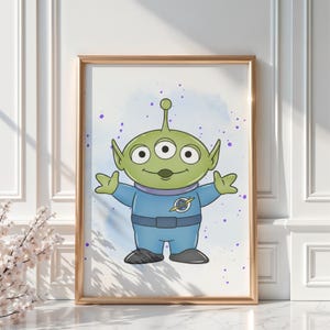May include: A framed print featuring a cartoon alien character with three eyes, green skin, and a blue jumpsuit. The alien has its arms outstretched against a light blue and purple speckled background. The frame is gold.