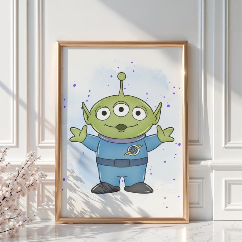 May include: A framed print featuring a cartoon alien character with three eyes, green skin, and a blue jumpsuit. The alien has its arms outstretched against a light blue and purple speckled background. The frame is gold.