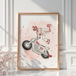 May include: A framed print featuring a cartoon illustration of a person in a white and red racing suit performing a stunt on a motorcycle. The motorcycle is white and red with black tires. The background is a light pink with red splatters.