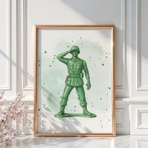 May include: A framed print featuring a green toy soldier saluting. The artwork has a watercolor effect with green splatters in the background. The soldier is in a classic pose, wearing a helmet and uniform.