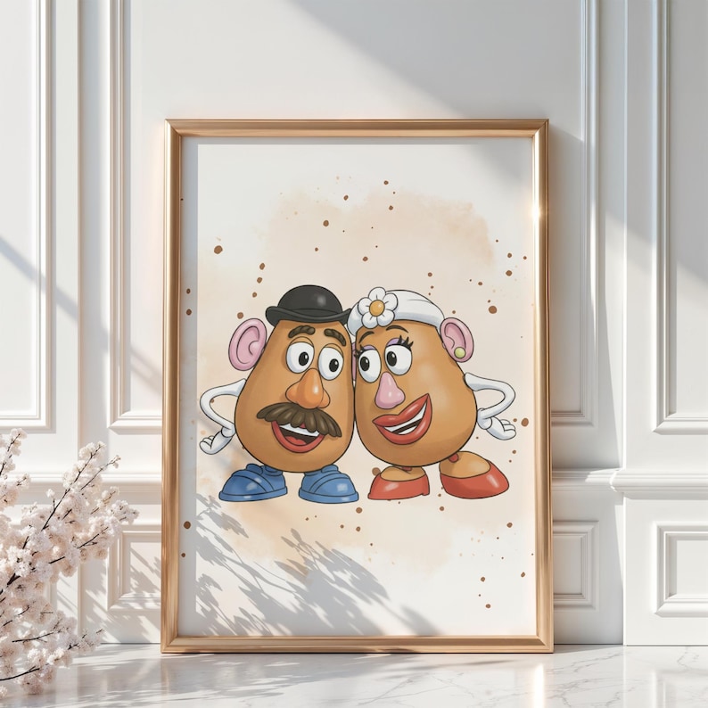 May include: Framed print featuring a cartoon couple, each with potato-shaped heads, large eyes, and smiling mouths. The male figure wears a black bowler hat and mustache, while the female figure has a flower in her hair. The background has a light brown watercolor effect.