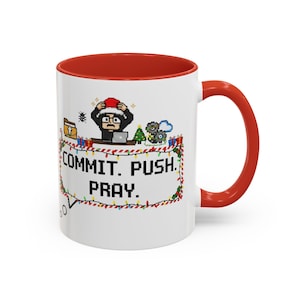 Könnte beinhalten: Weiße Keramiktasse mit rotem Innenraum und Henkel. Die Tasse zeigt ein pixeliges Design einer Person mit Weihnachtsmütze, Laptop und dem Text "COMMIT. PUSH. PRAY." umgeben von Lichterketten.