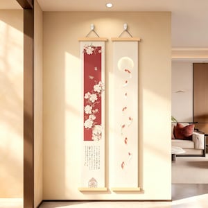 May include: Two vertical wall scrolls with wooden hangers. One features a red panel with white floral designs and calligraphy. The other scroll displays a full moon and koi fish. Both scrolls are cream-coloured with wooden accents.