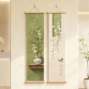 Puede incluir: Dos obras de arte murales verticales. Una presenta un fondo verde texturizado con un jarrón blanco con flores blancas, una pequeña repisa de madera y pájaros volando. La otra tiene un fondo crema con flores blancas, un pájaro y caligrafía.