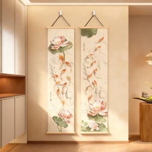 Peut inclure: Deux panneaux muraux verticaux avec un fond blanc cassé texturé. Chaque panneau présente une fleur de lotus, des feuilles vertes et des poissons koi orange. Les panneaux sont suspendus par des tiges en bois et des cordons noirs, créant une esthétique sereine inspirée de la nature.