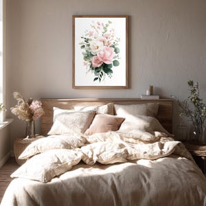 May include: A framed watercolor print of a floral bouquet featuring pink and white roses, green foliage, and delicate sprigs. The artwork is displayed above a bed with beige linens and pillows, creating a soft, inviting bedroom scene.