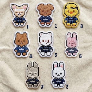 Könnte beinhalten: Eine Sammlung von acht gestickten Aufnähern mit pixeligen Tierdesigns. Jeder Aufnäher zeigt ein anderes Tier, darunter ein Fuchs, ein Bär, eine Ente, ein Kaninchen und ein Wolf, alle in einer marineblauen Uniform. Die Aufnäher sind weiß umrandet.