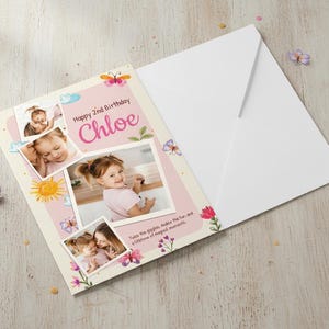 May include: A personalized birthday card for a 2-year-old named Chloe, featuring photos, butterflies, and floral accents. The card is open, with a white envelope beside it. The text reads "Happy 2nd Birthday Chloe."