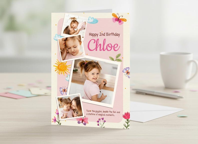 May include: A birthday card with photos of a young girl, featuring the text "Happy 2nd Birthday Chloe." The card has a pink and cream color scheme with floral and butterfly illustrations. The card is on a light-colored surface.