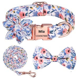 Peut inclure: Ensemble de collier pour chien à motifs floraux avec laisse et nœud papillon assortis. Le tissu blanc présente un motif de roses roses et de feuilles bleues. Le collier a une boucle or rose avec le nom "Mia" et un numéro de téléphone.