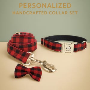 May include: A personalized handcrafted collar set for pets. The set includes a red and black plaid collar, leash, and bow tie. The collar has a silver buckle engraved with "Lily" and the number "929639".