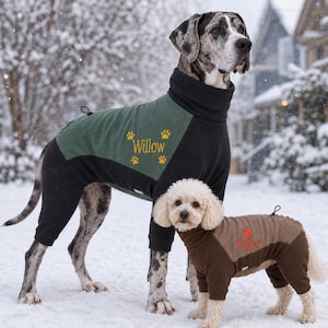 May include: A large Great Dane wearing a black and green fleece dog jumpsuit with the name Willow and paw prints embroidered in yellow. A small poodle wears a brown and tan fleece dog jumpsuit with the name Rufus and a red paw print.