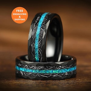 Könnte beinhalten: Ein schwarzer Ring mit facettierter Oberfläche und einer mittigen Einlage aus zerkleinertem blauem Opal. Das Band weist ein strukturiertes, metallisches Finish auf, das die leuchtend blaue Steineinlage umgibt. Der Ring ist in zwei Positionen abgebildet.