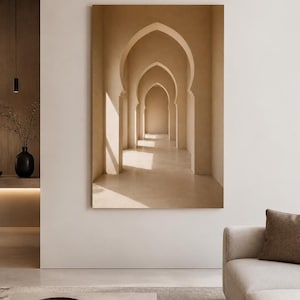 May include: A large rectangular wall art print featuring a series of beige, pointed archways receding into the distance. The image displays a warm, monochromatic color palette with soft sunlight casting distinct shadows across the floor and walls.