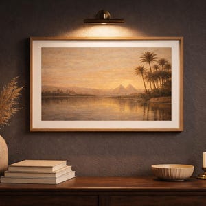 Peut inclure: Une impression encadrée d'un paysage avec des palmiers, des pyramides et un plan d'eau au coucher du soleil. L'œuvre est exposée au-dessus d'une surface en bois avec un vase, des livres et un bol.