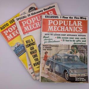 May include: Three vintage Popular Mechanics magazines from 1961 and 1962. The November 1961 issue features a blue 1962 Ford Fairlane being washed. The covers include text such as 'Special: 10 Hideaway Vacations' and 'Keys to Lower-Cost Appliance Repairs'.
