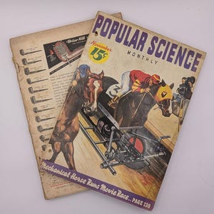 May include: Two vintage magazines. The top magazine cover reads "Popular Science Monthly" with "November 15¢" in a yellow circle. The cover art depicts a horse race. The bottom magazine has a pipe advertisement.