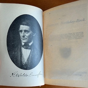 Puede incluir: Un libro abierto con un retrato en blanco y negro de un hombre con traje y pajarita. El texto "R. Waldo Emerson" est&aacute; debajo del retrato. La p&aacute;gina derecha tiene el texto "Birthday-Book."
