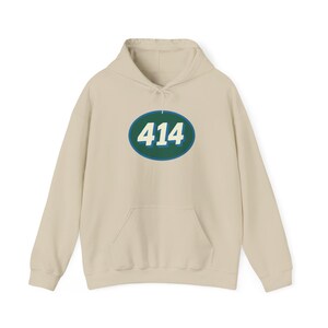 May include: A cream-coloured hooded sweatshirt with a front pocket and a drawstring. The sweatshirt features a green and blue oval graphic with the number "414" in white. The design is centred on the chest.