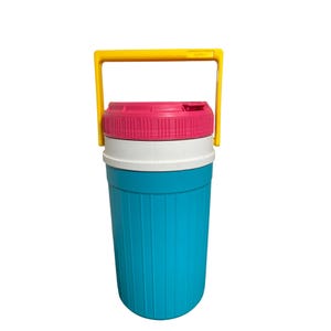 Puede incluir: Una nevera portátil colorida de estilo retro con un asa amarilla brillante. La nevera tiene una base turquesa, una sección media blanca y una tapa rosa. El asa es arqueada y resistente, diseñada para facilitar el transporte. Ideal para picnics.