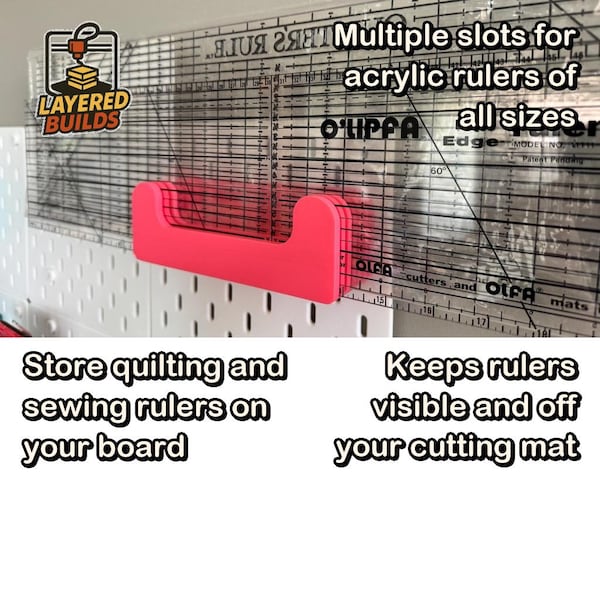 May include: A bright pink plastic wall-mounted storage rack featuring multiple slots designed to hold acrylic quilting and sewing rulers. The rack is attached to a white pegboard, with a clear ruler inserted into the slots for display.