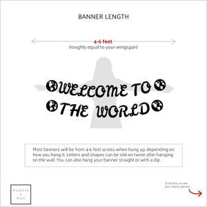 May include: A white banner with black text that reads "WELCOME TO THE WORLD" with a globe icon on either side of the text. The banner is 4-6 feet long and can be hung straight or with a dip.