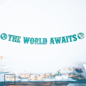 May include: A teal blue banner with the text "The World Awaits" and globe illustrations on each end. The banner is hanging on a white wall above a table with food and drinks.