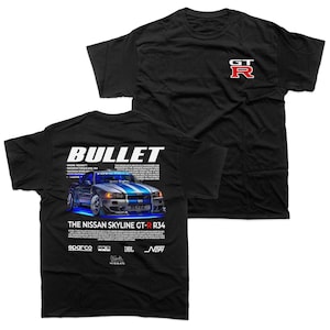 May include: Black t-shirt featuring a graphic of a silver and blue Nissan Skyline GT-R R34 car with the word "BULLET" above it. The shirt also has the text "GT R" in red and white on the front.