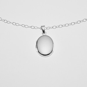 May include: A silver chain necklace with a plain oval locket pendant.