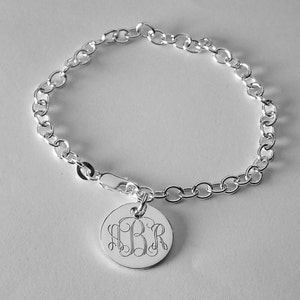 May include: A silver chain bracelet with a round charm featuring a monogrammed "M.B.R."