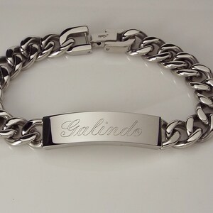 May include: A silver chain bracelet with a rectangular tag engraved with the name "Galindo".