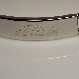 May include: A silver chain bracelet with a rectangular tag engraved with the name "Alissia".