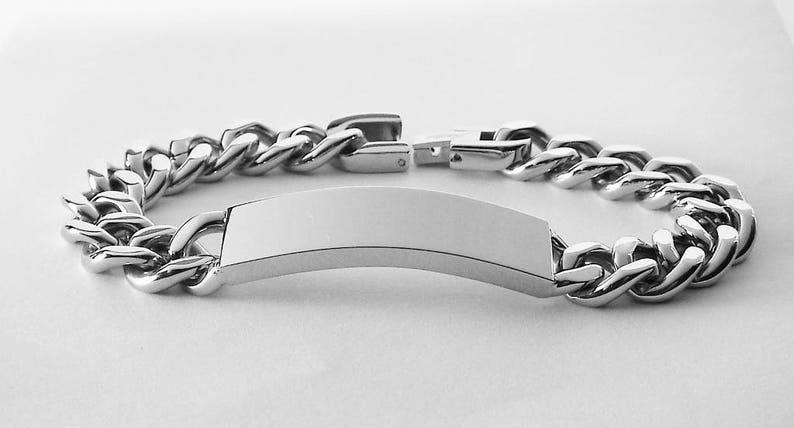 May include: A silver chain bracelet with a blank rectangular tag. The chain is a curb style.