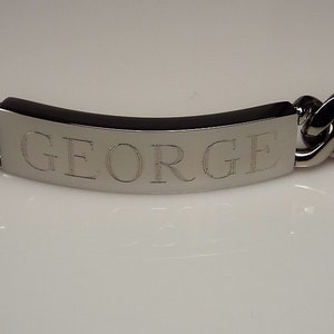 May include: A silver chain bracelet with a rectangular tag engraved with the name "GEORGE".