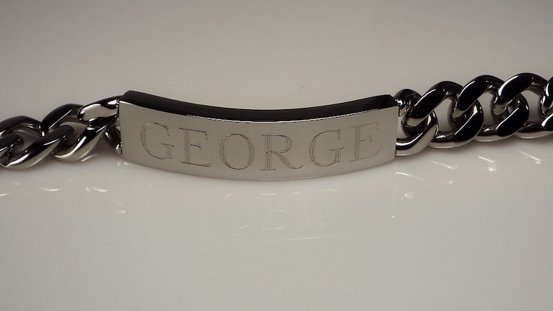 May include: A silver chain bracelet with a rectangular tag engraved with the name "GEORGE".