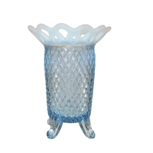 May include: A light blue glass vase with a diamond pattern and a white, scalloped rim. The vase has three legs and is perfect for displaying flowers.