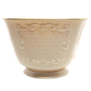 May include: A white ceramic bowl with a gold rim and an intricate embossed design. The bowl has a scalloped edge and a wide, round base.