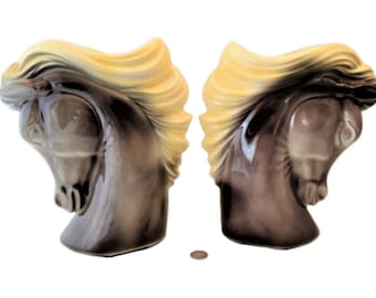 May include: A pair of ceramic horse head bookends. The bookends are brown with a yellow mane and tail. They are facing each other.