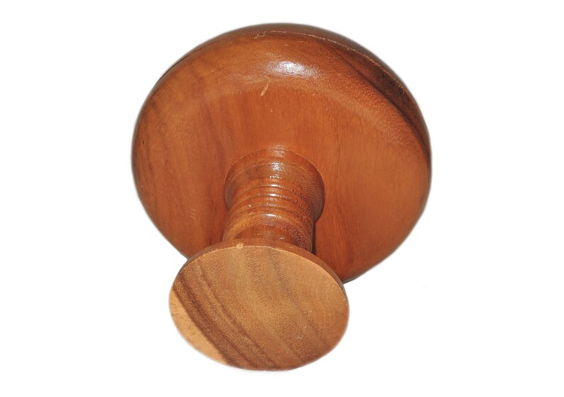May include: A wooden pedestal with a round top and a round base. The pedestal is made of light brown wood and has a smooth finish.