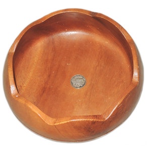 May include: A round wooden bowl with a slightly scalloped edge. The bowl is made of light brown wood and has a smooth, polished finish.