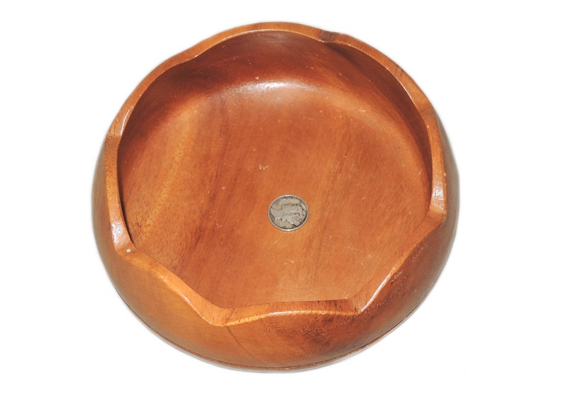 May include: A round wooden bowl with a slightly scalloped edge. The bowl is made of light brown wood and has a smooth, polished finish.
